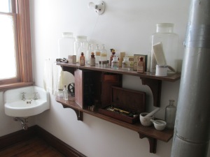The photo shows the sink in the Apothecary room at Banting House and two shelves holding medicine bottles, vials, and supplies, as well as pestle and mortar bowls.